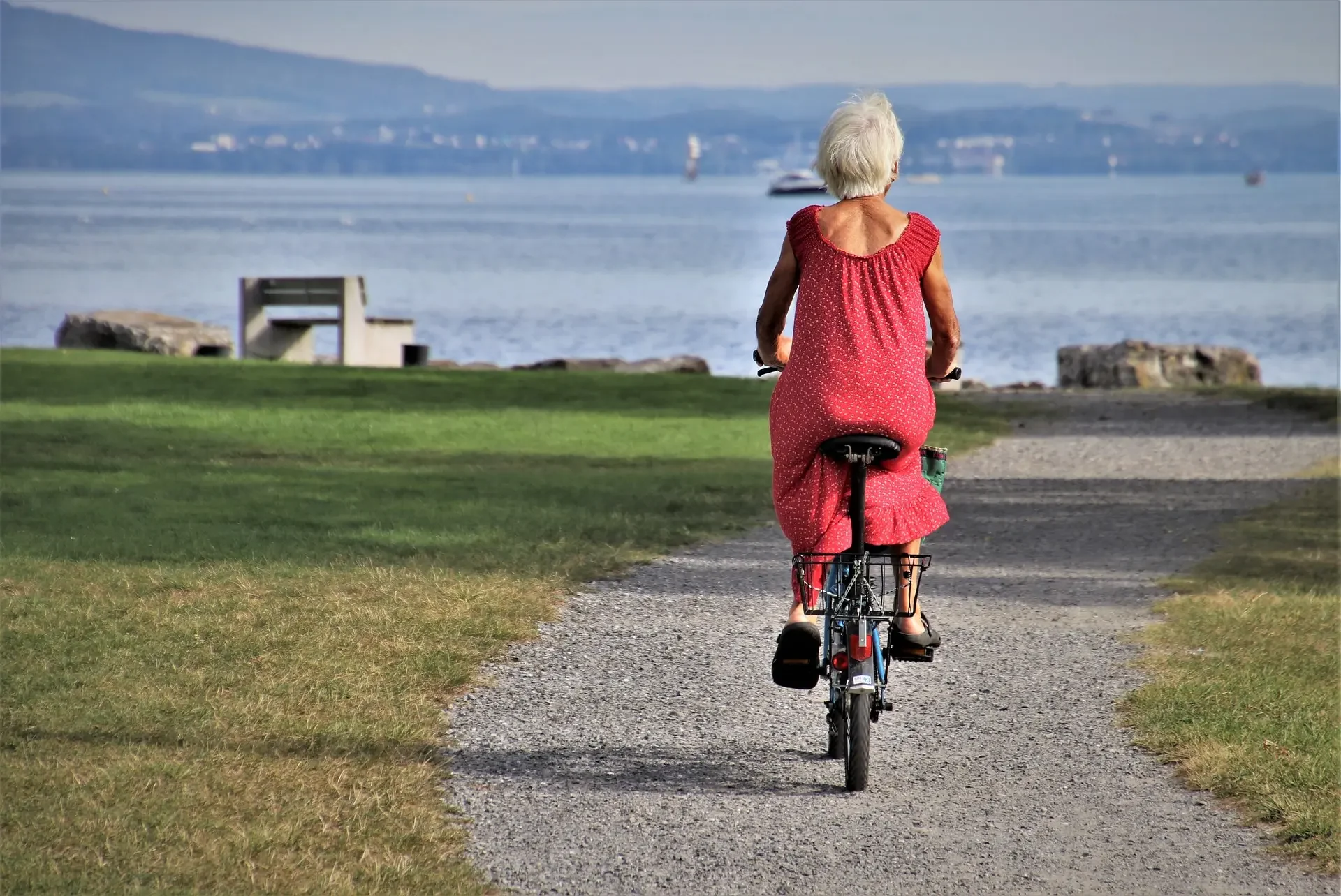 Older woman cycling beside the water.
